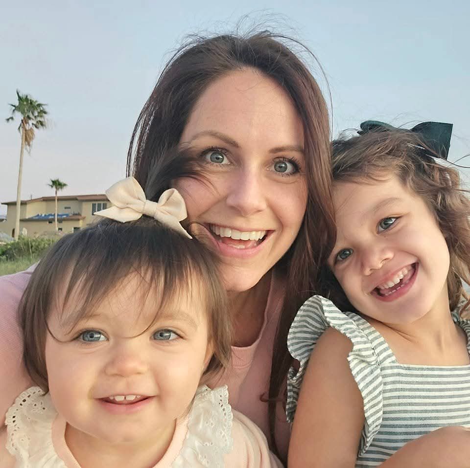 Sarah Webster smiling at the beach with her two daughters
