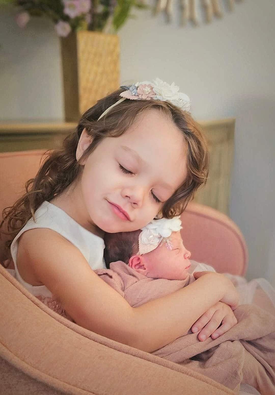 Big sister cuddling her newborn sister