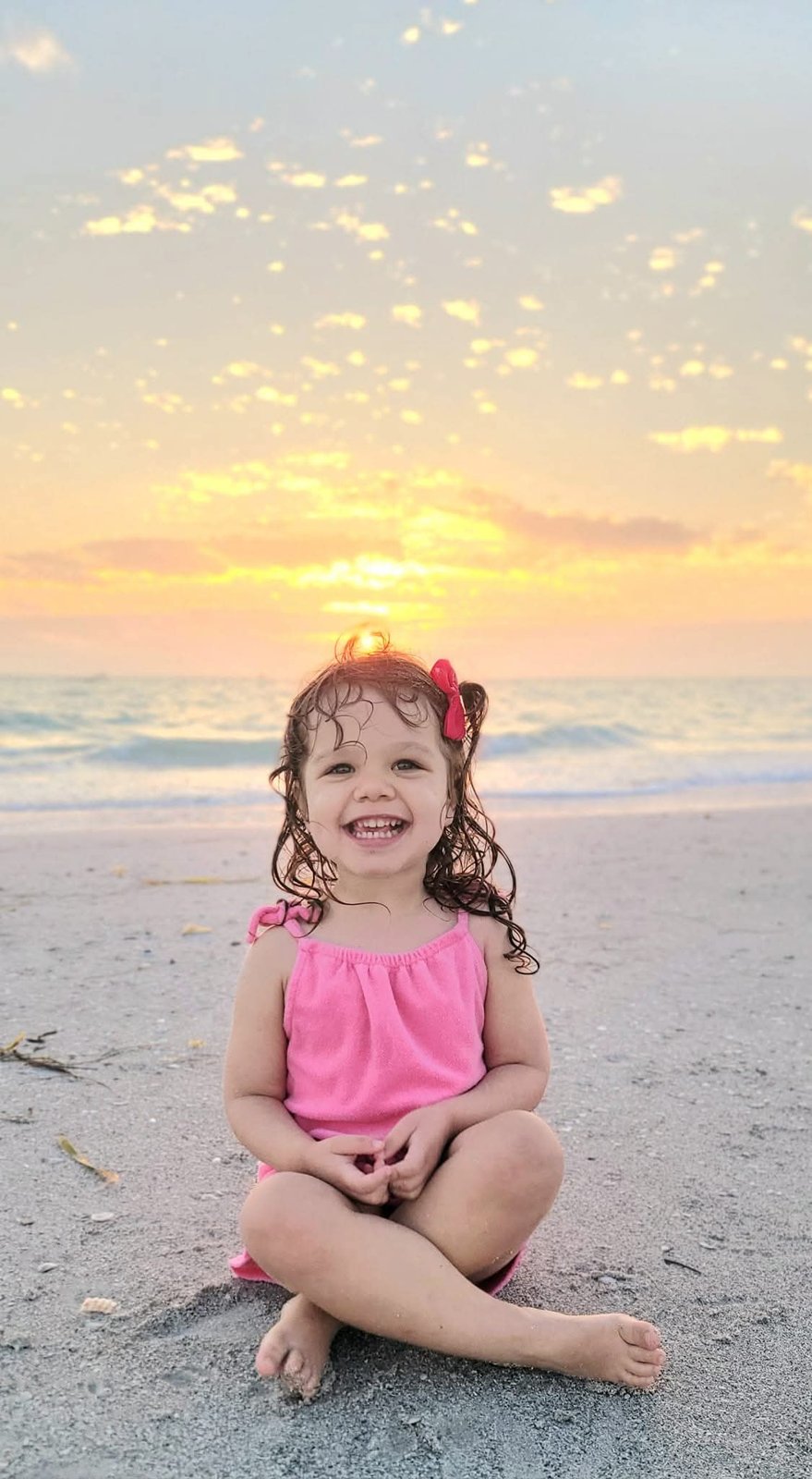 Little girl laughing on the beach at sunset