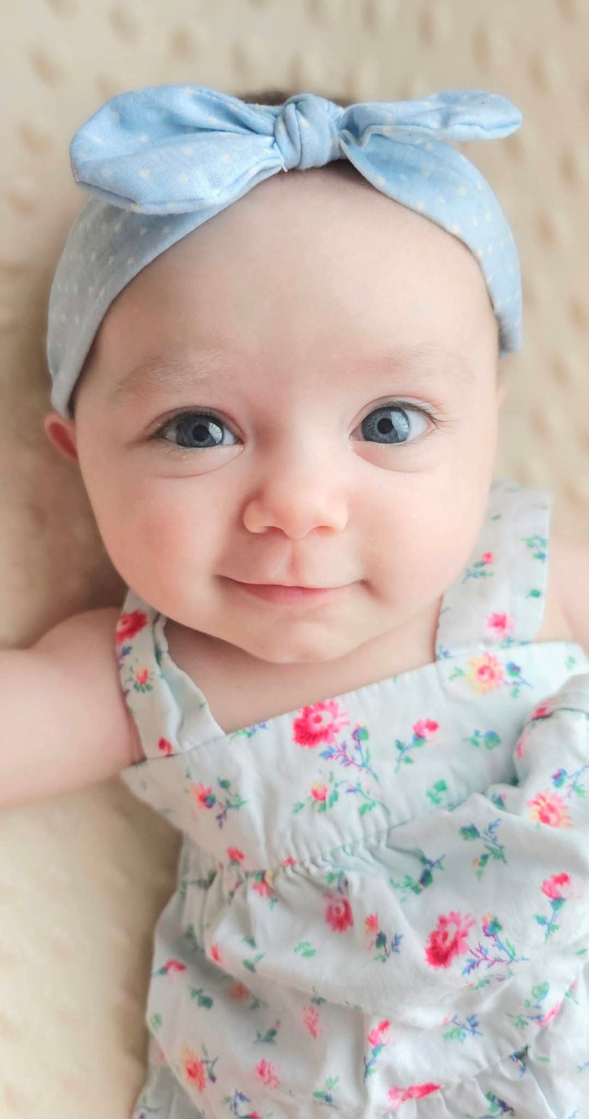 Baby in a blue polka-dot headband smiling