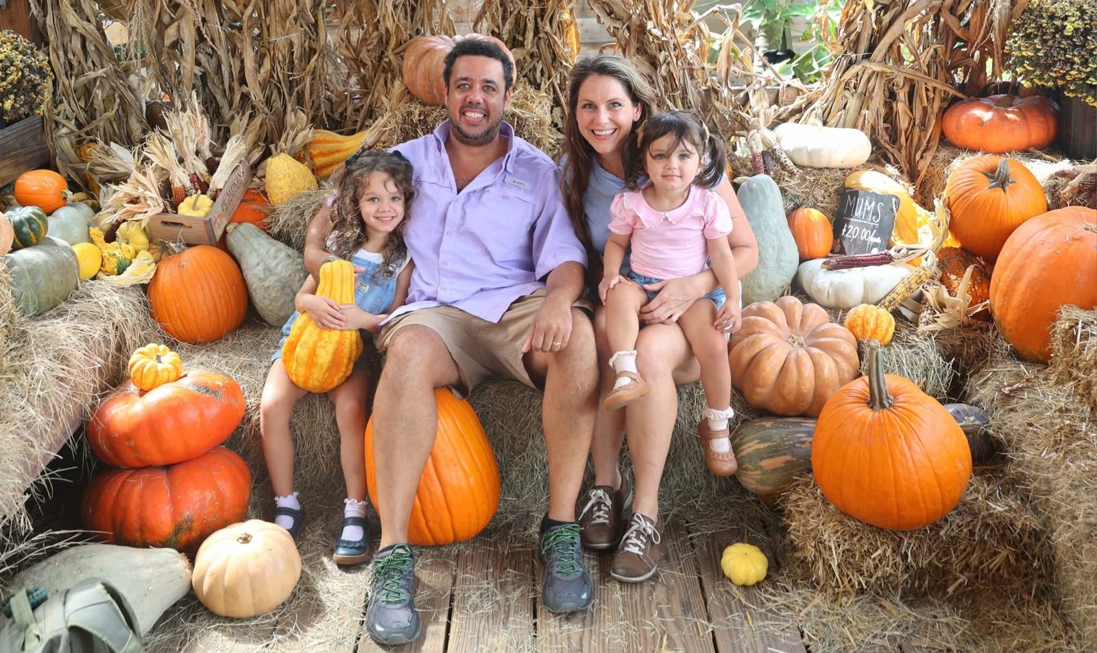 Family of four among pumpkins and hay bales