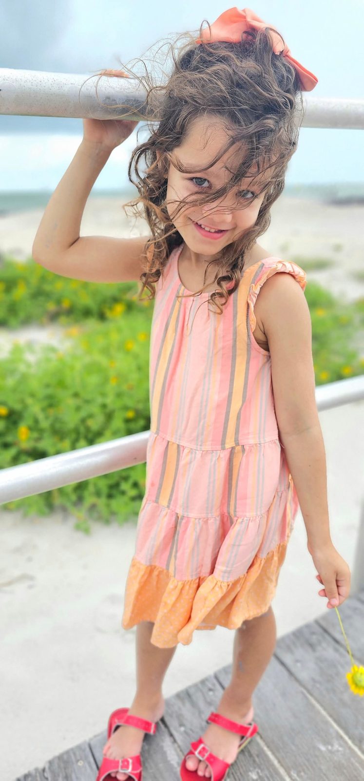 Girl with windswept curls at a beach railing