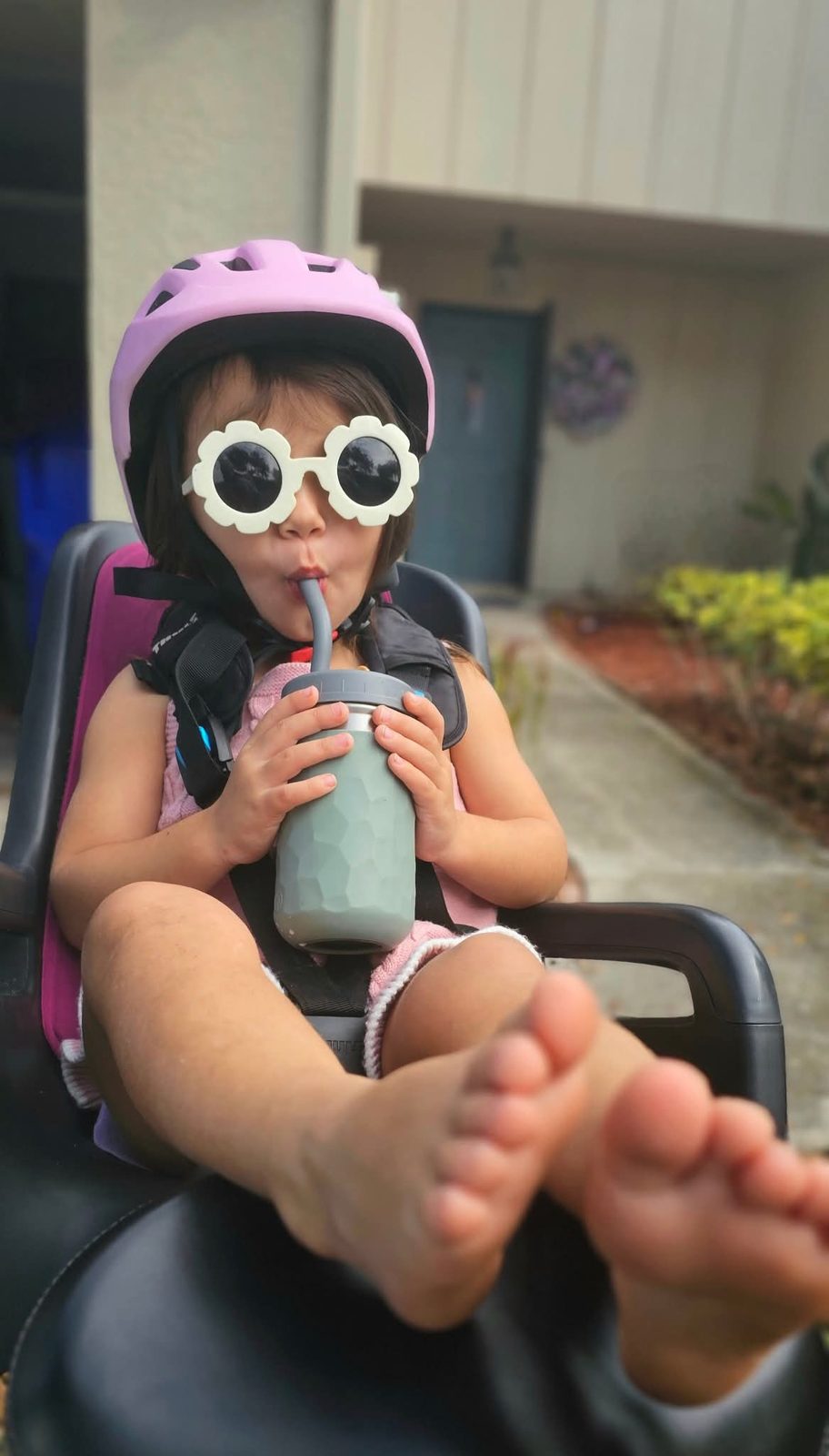 Toddler in flower sunglasses sipping from a cup